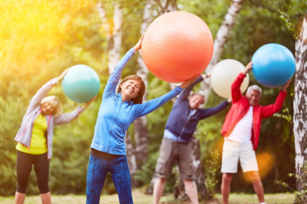 group of active seniors exercising outdoors with big colorful balls as an example of 12 fun recreational activities for senior citizens