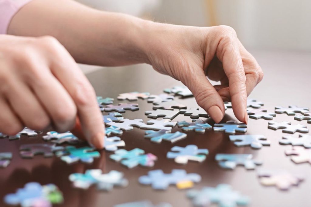 close up of hands working a jigsaw puzzle as a representation of memory care activities for seniors with dementia