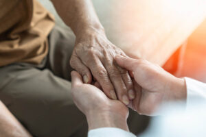 a pair of younger hands comforts a pair of older ones as someone explains respite care for seniors