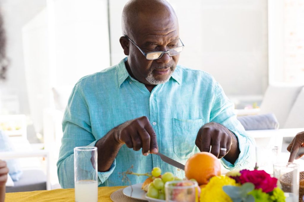 older man preparing nutritious meal of fresh fruits and vegetables as part of 6 health habits for seniors
