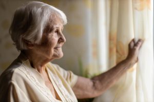 elderly woman looking out window wondering how do you know when its time for memory care
