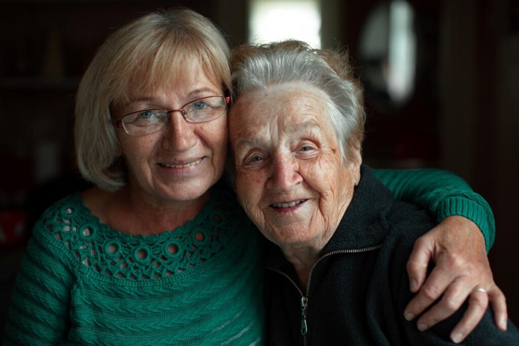middle-aged woman hugging an elderly woman as they discuss how to create a plan for respite care for seniors