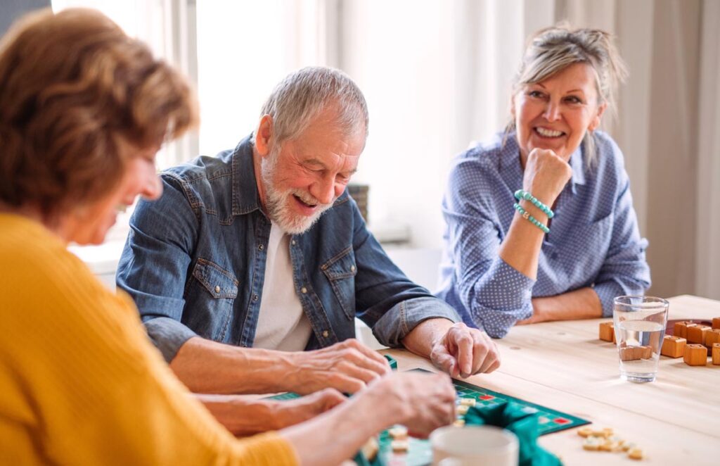 group of senior citizens sitting around a table playing a game and engaging in one of 10 indoor recreational activities for seniors
