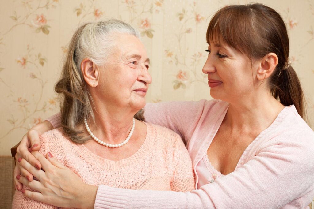 middle-aged woman hugging her mother asking herself can my mom with dementia stay in assisted living