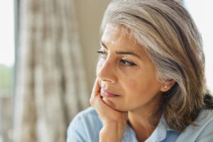 older woman looking pensive and reflective asking herself what are the signs of dementia