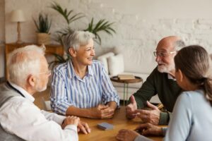 a group of senior citizens gathered around the table discussing the 5 benefits of respite care