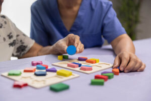 a couple of senior citizens seated at a table playing a colorful matching game as part of memory care activities for seniors with dementia