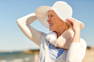 Older woman wearing a large sunhat and enjoying the sunshine outdoors but who wants to know what is sundowning?